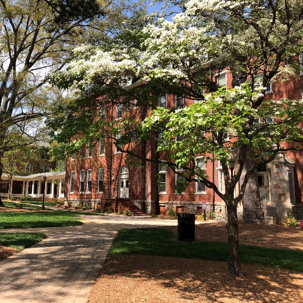 White flowers sit in the forefront with Agnes Scott "Main" Hall behind the plants